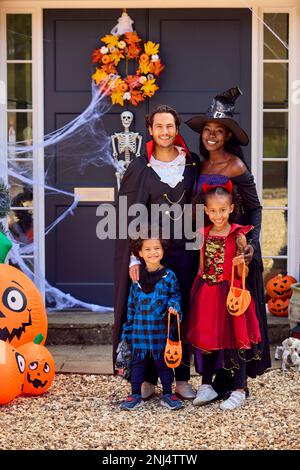 Porträt Der Familie, Die Sich Für Halloween Verkleidet, Vor Dem Haus Bereit Für Süßes Oder Saures Stockfoto