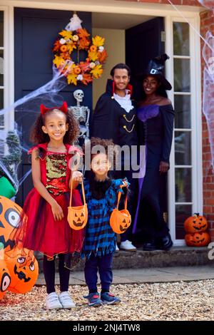 Porträt Der Familie, Die Sich Für Halloween Verkleidet, Vor Dem Haus Bereit Für Süßes Oder Saures Stockfoto