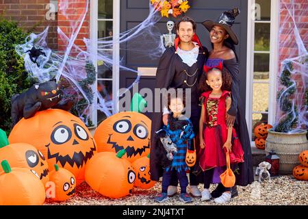 Porträt Der Familie, Die Sich Für Halloween Verkleidet, Vor Dem Haus Bereit Für Süßes Oder Saures Stockfoto