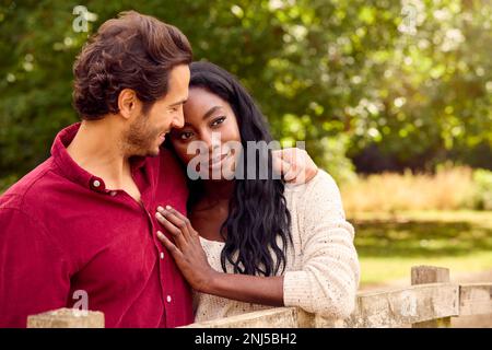 Ein Liebenswertes Gemischtes Rennpaar, Das Sich Auf Dem Land Auf Den Zaun Lehnt Stockfoto