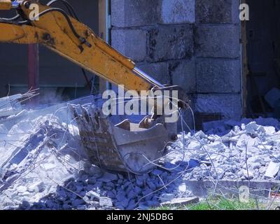 Die Schaufel eines Hydraulikbaggers sammelt den Schutt nach einem Abriss Stockfoto