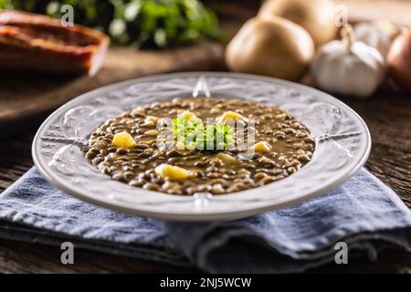 Linsen- und Kartoffelsuppe oder Eintopf auf einem rustikalen Teller mit Petersilie. Stockfoto