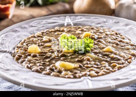 Linsen- und Kartoffelsuppe oder Eintopf auf einem rustikalen Teller mit Petersilie. Stockfoto