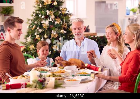 Familie Der Ganzen Generation Feiert Weihnachten Zu Hause Und Betet Vor Dem Gemeinsamen Essen Stockfoto