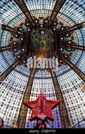 Die Kuppel des Gebäudes in Galeries Lafayette, dem Pariser Kaufhaus. Im Rahmen ist der Stern auf dem Weihnachtsbaum. Stockfoto