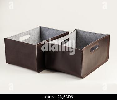 Zwei braune Aufbewahrungsboxen aus echtem Leder mit grauem Filz. Elegantes, handwerkliches Zubehör zur Organisation von Garderobe oder Arbeitsplatz Stockfoto