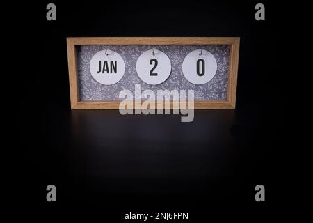 Ein hölzerner Kalenderblock, der das Datum Januar 20. auf dunkelschwarzem Hintergrund zeigt. Notieren Sie sich das Datum oder das Datum des Ereignisses. Konzept Stockfoto