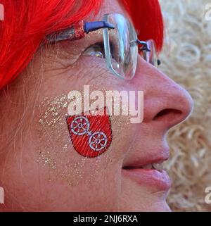 Lady genießt die Mainz Fastnacht, Shrove Monday, in einer roten Perücke mit temporärem Tattoo in Rot auf das Wappen der Stadt, Februar 2023 Stockfoto