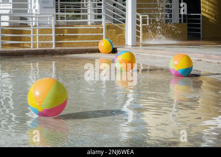 Strandbälle schweben an einem Sommertag im Wasser eines Resortpools. Stockfoto