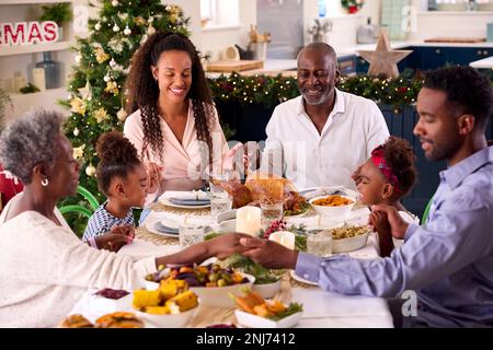 Familie Der Ganzen Generation Feiert Weihnachten Zu Hause Und Betet Vor Dem Gemeinsamen Essen Stockfoto