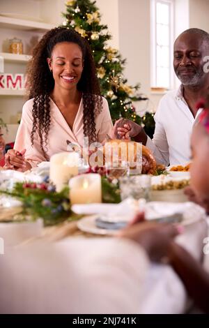 Familie Der Ganzen Generation Feiert Weihnachten Zu Hause Und Betet Vor Dem Gemeinsamen Essen Stockfoto