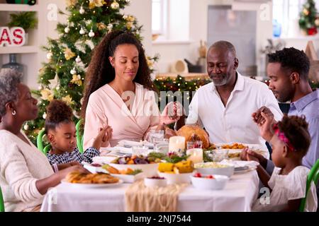 Familie Der Ganzen Generation Feiert Weihnachten Zu Hause Und Betet Vor Dem Gemeinsamen Essen Stockfoto