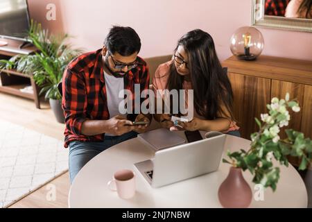 Ernsthafte Ehefrau und Ehemann planen Budget, prüfen Finanzen, fokussierte junge Frau mit Online-Rechner und Zählen von Rechnungen oder Steuern, Mann mit Laptop Stockfoto