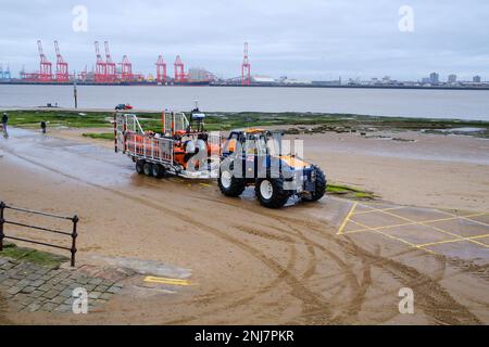 New Brighton Rettungsboot-Crew holt das Boot wieder am Strand ab, wobei der Traktor die Rippe auf einem Anhänger zieht, nachdem er eine Rettung auf dem Meer abgeschlossen hat Stockfoto