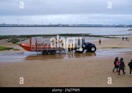 New Brighton Rettungsboot-Crew holt das Boot wieder am Strand ab, wobei der Traktor die Rippe auf einem Anhänger zieht, nachdem er eine Rettung auf dem Meer abgeschlossen hat Stockfoto