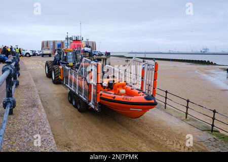 New Brighton Rettungsboot-Crew holt das Boot wieder am Strand ab, wobei der Traktor die Rippe auf einem Anhänger zieht, nachdem er eine Rettung auf dem Meer abgeschlossen hat Stockfoto