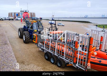 New Brighton Rettungsboot-Crew holt das Boot wieder am Strand ab, wobei der Traktor die Rippe auf einem Anhänger zieht, nachdem er eine Rettung auf dem Meer abgeschlossen hat Stockfoto