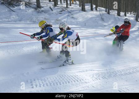 Skifahrer, die von einer kostenlosen Ski-doo-Schneemobilfahrt abgeschleppt werden. Mount Amiata, Toskana, Italien Stockfoto