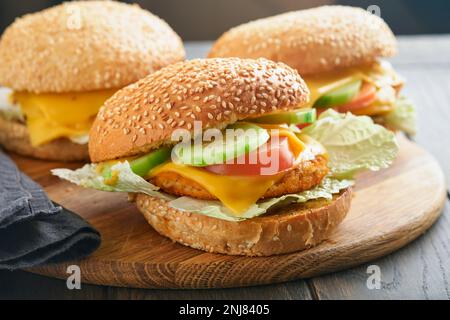 Hausgemachte Fischburger mit Gemüse auf rustikalem Holzbrett. Seitenansicht, Nahaufnahme. Menü. Stockfoto