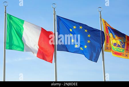 Venedig, VE, Italien - 6. November 2022: Drei große Flaggen Italien Europa und Venetien Region Stockfoto