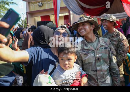 USA Sofia Rivera Figueroa, Nachrichtenanalytikerin der Hauptquartier- und Hauptquartier-Kompanie, 3. Infanterie-Brigaden-Kampfteam, 25. Infanterie-Division, Lächelt für ein Foto mit Mitgliedern der Menge während einer Community Outreach-Aufführung der Tropic Lightning Brass Band der 25. Infantry Division im Rahmen von Super Garuda Shield 2022 am 6. August 2022 im Taman Tani Merdeka Park, Martapura, South Sumatra, Indonesien. Super Garuda Shield 2022, ein Teil von Operation Pathways und eine langjährige jährliche, bilaterale Militärübung zwischen den USA Militär und indonesischer Staatsangehöriger Stockfoto