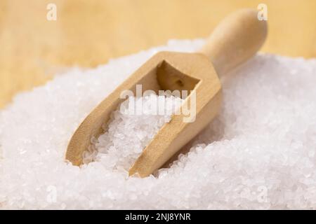 Ein Studiofoto einer kleinen Holzschaufel in einem Haufen grobes Salz. Stockfoto