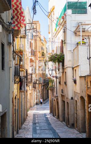 TARRAGONA, SPANIEN - 6. AUGUST 2022: Schmale Straße in der Altstadt von Tarragona, einer touristischen Hafenstadt am Mittelmeer im Nordosten Spaniens. Stockfoto