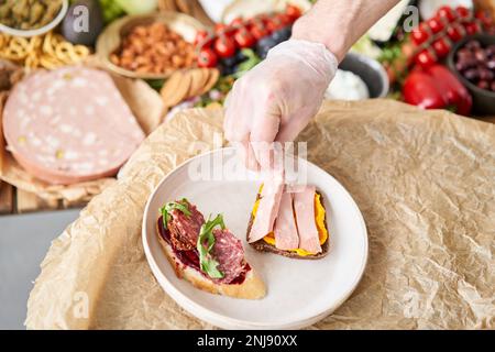 Der Kellner macht Bruschetta oder Tapas. Tisch voller mediterraner Vorspeisen, Tapas oder Antipasto. Auswahl an italienischen Speisen. Köstlicher Snack auf der Party Stockfoto