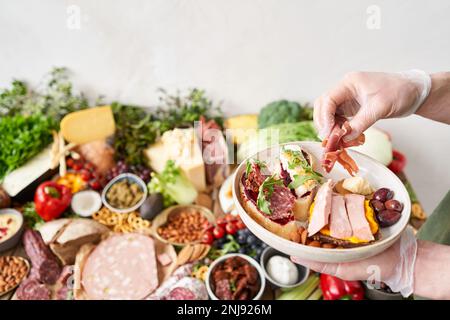 Der Kellner macht Bruschetta oder Tapas. Tisch voller mediterraner Vorspeisen, Tapas oder Antipasto. Auswahl an italienischen Speisen. Köstlicher Snack auf der Party Stockfoto