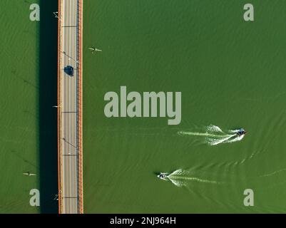 Luftaufnahme der Brücke über den Segre in Mequinenza und Kajaks und Boote, die auf dem Fluss segeln (Bajo Cinca, Saragoza, Aragon, Spanien) Stockfoto