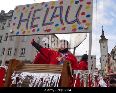 Würzburg, Bayern, 19. Februar 2023. Verkleidete Frau steht auf einem Wagen unter dem Banner mit traditioneller Begrüßung der Karnevalsparade (Fasching) Stockfoto