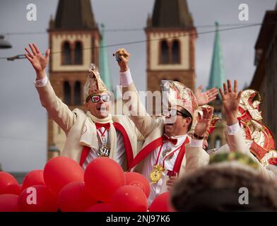 Würzburg, Bayern, 19. Februar 2023. Männer in Narren-Hüten und lustigen Gläsern mit Kathdral im Hintergrund bei der Karnevalsparade (Fasching) Stockfoto