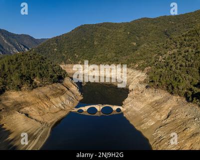 Luftaufnahme der mittelalterlichen Brücke von Querós, im Susqueda-Reservoir, sichtbar während einer Dürre mit 36 % Wasserstand (Katalonien, Spanien) Stockfoto