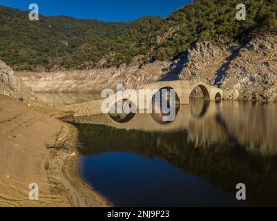 Luftaufnahme der mittelalterlichen Brücke von Querós, im Susqueda-Reservoir, sichtbar während einer Dürre mit 36 % Wasserstand (Katalonien, Spanien) Stockfoto