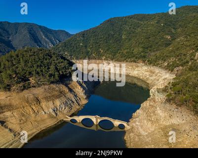 Luftaufnahme der mittelalterlichen Brücke von Querós, im Susqueda-Reservoir, sichtbar während einer Dürre mit 36 % Wasserstand (Katalonien, Spanien) Stockfoto