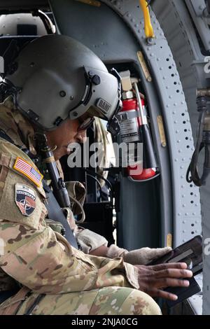 Ein US-Soldat, der dem 1-230.-Kampfhubschrauberbataillon der Tennessee Army National Guard zugeteilt ist, führt im Rahmen einer Probe für den Northern Strike 22 Over Camp Grayling, Michigan, vor dem Flug in einem UH-60 Blackhawk Helikopter Kontrollen durch, die am 6. August 2022 stattfinden. Northern Strike wurde entwickelt, um 7.400-Servicemitarbeiter mit verschiedenen Schulungsformen herauszufordern, die die Interoperabilität zwischen mehreren Komponenten, multinationalen und behördenübergreifenden Partnern fördern. Stockfoto