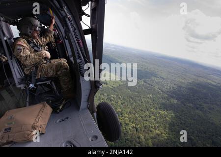 Ein US-Soldat, der dem 1-230.-Kampfhubschrauberbataillon der Tennessee Army National Guard zugeteilt wurde, bereitet sich auf die Landung in einem UH-60 Blackhawk Helikopter im Rahmen der Pre-Unfall Plan Prohearsal for Northern Strike 22 Over Camp Grayling, Michigan, 6. August 2022, vor. Northern Strike wurde entwickelt, um 7.400-Servicemitarbeiter mit verschiedenen Schulungsformen herauszufordern, die die Interoperabilität zwischen mehreren Komponenten, multinationalen und behördenübergreifenden Partnern fördern. Stockfoto