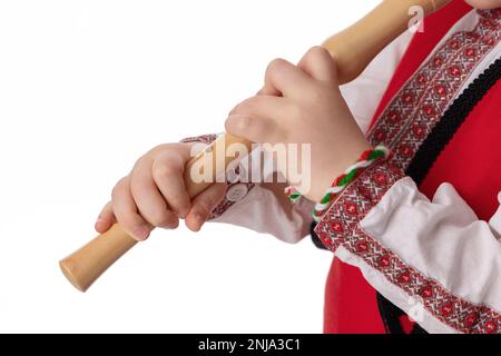 Bulgarischer Junge in traditionellen Folkloresachen mit Frühlingsblumen, Schneetropfen und handgefertigten Wollarmband Martenitsa Symbol von Baba Marta Stockfoto