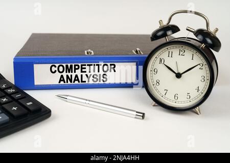 Geschäftskonzept. Auf einer weißen Oberfläche, einem Weckrechner und einem Ordner mit der Aufschrift - COMPETITOR ANALYSIS Stockfoto