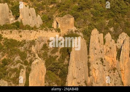 Details der Roques de la Vila in Finestres (auch bekannt als Muralla de Finestres) und der Einsiedlung von San Vicente zwischen den Felsen bei Sonnenuntergang, Spanien Stockfoto