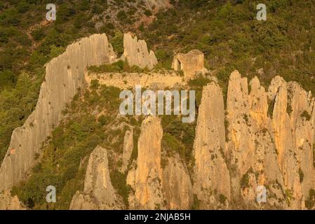 Details der Roques de la Vila in Finestres (auch bekannt als Muralla de Finestres) und der Einsiedlung von San Vicente zwischen den Felsen bei Sonnenuntergang, Spanien Stockfoto