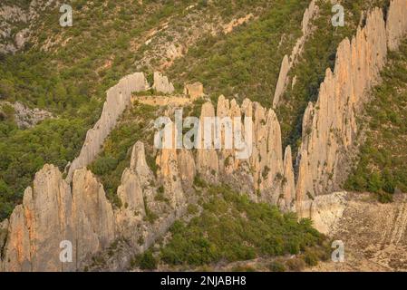 Details der Roques de la Vila in Finestres (auch bekannt als Muralla de Finestres) und der Einsiedlung von San Vicente zwischen den Felsen bei Sonnenuntergang, Spanien Stockfoto