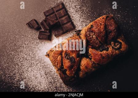 Ein frisch gebackenes Schokoladenbrötchen mit zwei dreieckigen Stücken köstlicher Schokolade, die strategisch auf der Oberseite platziert wurden Stockfoto