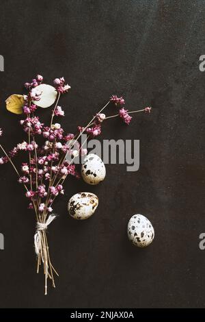 Wachteleier und ein Strauß Frühlingsblumen auf rustikalem, strukturiertem Hintergrund Stockfoto