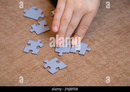 Kinderhände sammelt Puzzles auf dem Boden auf einer braunen Fliesenansicht von oben Stockfoto