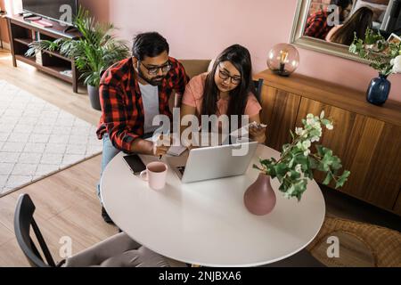 Ernsthafte Ehefrau und Ehemann planen Budget, prüfen Finanzen, fokussierte junge Frau mit Online-Rechner und Zählen von Rechnungen oder Steuern, Mann mit Laptop Stockfoto