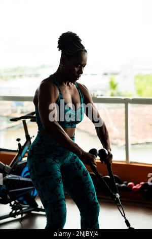 Eine muskuläre Frau, die Muskeln in den Armen und Schultern trainiert. Fitnessübungen im Studio. Stockfoto