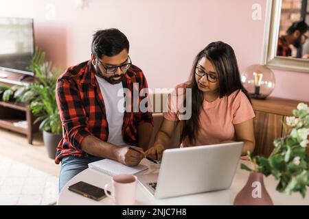 Ernsthafte Ehefrau und Ehemann planen Budget, prüfen Finanzen, fokussierte junge Frau mit Online-Rechner und Zählen von Rechnungen oder Steuern, Mann mit Laptop Stockfoto