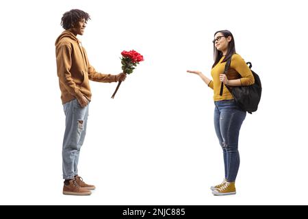 Junger afroamerikanischer Mann, der einer Studentin rote Rosen gibt, isoliert auf weißem Hintergrund Stockfoto