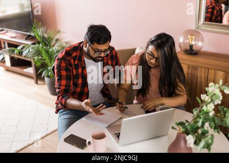 Ernsthafte Ehefrau und Ehemann planen Budget, prüfen Finanzen, fokussierte junge Frau mit Online-Rechner und Zählen von Rechnungen oder Steuern, Mann mit Laptop Stockfoto
